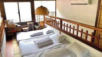 Una habitación con una cama, cabecera de madera, lámpara colgante, una mesita de noche con lámpara y una ventana con vistas.