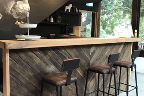 A bar area with a wooden counter, two stools, and a view of the outdoors. - Soundwater (Miaoli)