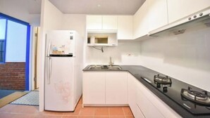 A compact kitchen with white cabinets, a built-in microwave, and a gas stove. - Soundwater (Miaoli)