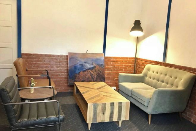 Una habitación con pared de ladrillo, un cuadro, un sofá, una mesa de centro y una lámpara.