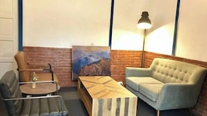 A room with a brick wall, a painting, a sofa, a coffee table, and a lamp. - Soundwater (Miaoli)