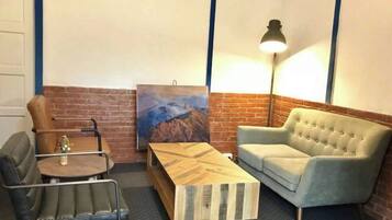 Una habitación con pared de ladrillo, un cuadro, un sofá, una mesa de centro y una lámpara.