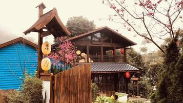 A traditional Japanese-style building with a wooden structure, a blue exterior, and a garden with flowering plants.