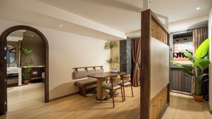 A modern dining area with a wooden table and chairs, a bench, and a potted plant. - Lune Boutique Hotel & Apartment Da nang (Da Nang)
