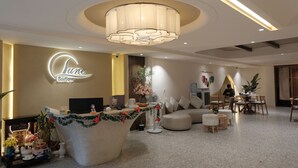 A modern hotel lobby with a reception desk, a large chandelier, and a seating area with a sofa and chairs. - Lune Boutique Hotel & Apartment Da nang (Da Nang)