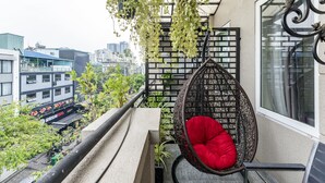 A balcony with a hanging chair, a view of a cityscape, and a restaurant in the background. - Edoya Hotel Phu My Hung (Ho Chi Minh City)
