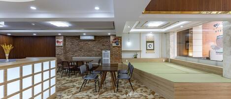A modern hotel lobby with a reception desk, seating area, and a pool table.