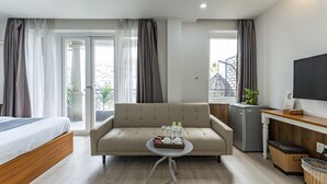 A modern hotel room with a bed, sofa, TV, and a small table with a tray of items. - Edoya Hotel Phu My Hung (Ho Chi Minh City)