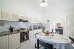 Una cocina con comedor, que incluye estufa, horno, armarios y una mesa lista para comer.