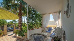 A sunlit patio with a wicker chair, a blue pot with a succulent, and a yellow umbrella. - Villa Calò 2 with Garden, 200 meters from Sea, Maruggio, Italy (Maruggio)