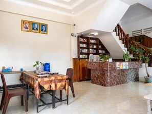 A dining area with a table set for two, a bookshelf, and a staircase leading to an upper level. - AHHA Residence Kampot (Kampot)