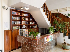 A reception desk with a marble top, surrounded by wooden shelves filled with books and magazines. - AHHA Residence Kampot (Kampot)