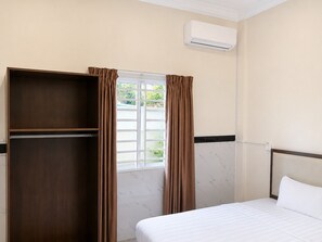 A hotel room with a bed, a wardrobe, a window with curtains, and an air conditioning unit. - AHHA Residence Kampot (Kampot)