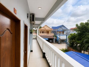 A balcony with a view of residential buildings, a tiled floor, and a wooden door with a number plaque. - AHHA Residence Kampot (Kampot)