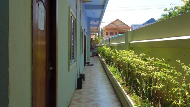 A corridor with a tiled floor, a wooden door, and a window with a notice. - AHHA Residence Kampot (Kampot)