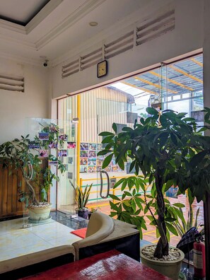 A room with a glass partition, potted plants, a clock, and a view of the outside. - AHHA Residence Kampot (Kampot)
