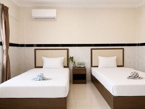A hotel room with two beds, a nightstand, a plant, and an air conditioning unit. - AHHA Residence Kampot (Kampot)