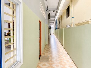 A corridor with a tiled floor, a wooden door, and a window with a wooden frame. - AHHA Residence Kampot (Kampot)