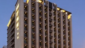 Un hôtel à plusieurs étages, doté d’une façade uniforme, de fenêtres régulièrement espacées et d’un toit plat.