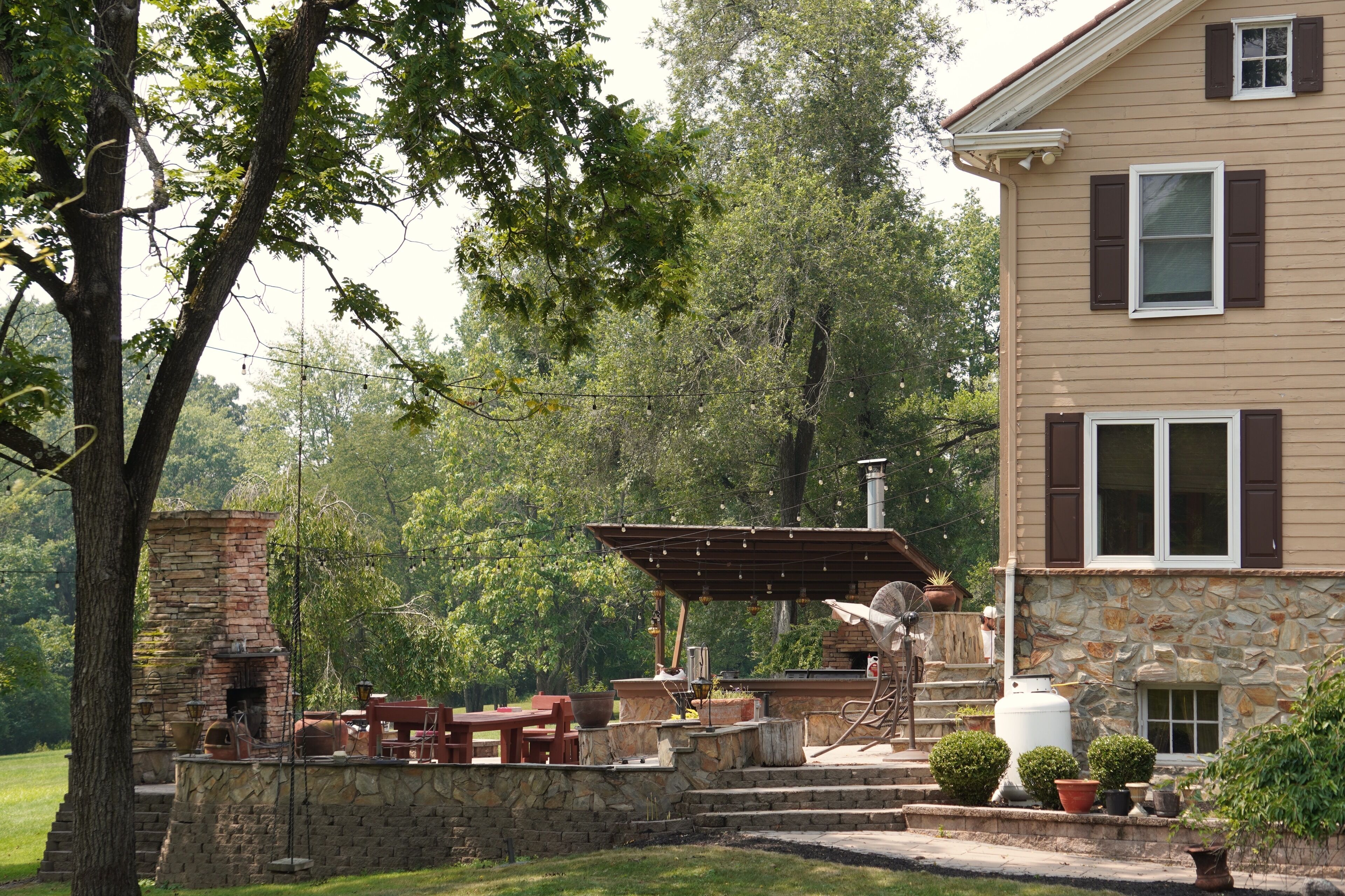 A stone fireplace, outdoor seating, and a pergola with string lights.
