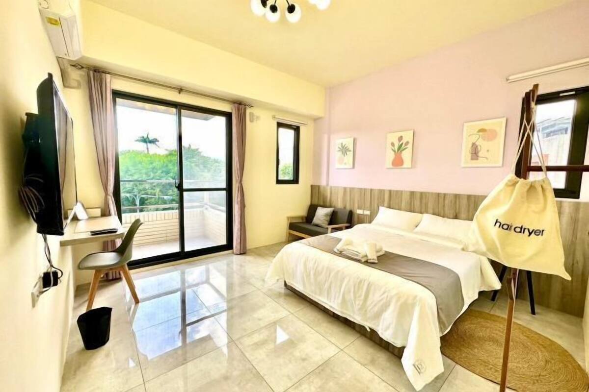 Una camera d'albergo con un letto, una scrivania, una sedia, una TV e vista sul verde.