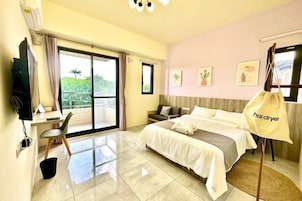 Habitación de hotel con cama, escritorio, silla, televisor y vistas a zonas verdes.
