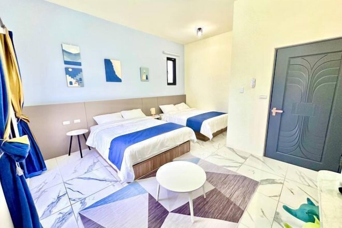 Una camera d'albergo con due letti, un tavolino piccolo e una porta con maniglia decorativa.