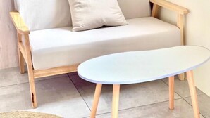 Une pièce moderne avec un canapé de couleur claire et une table ronde aux pieds en bois.