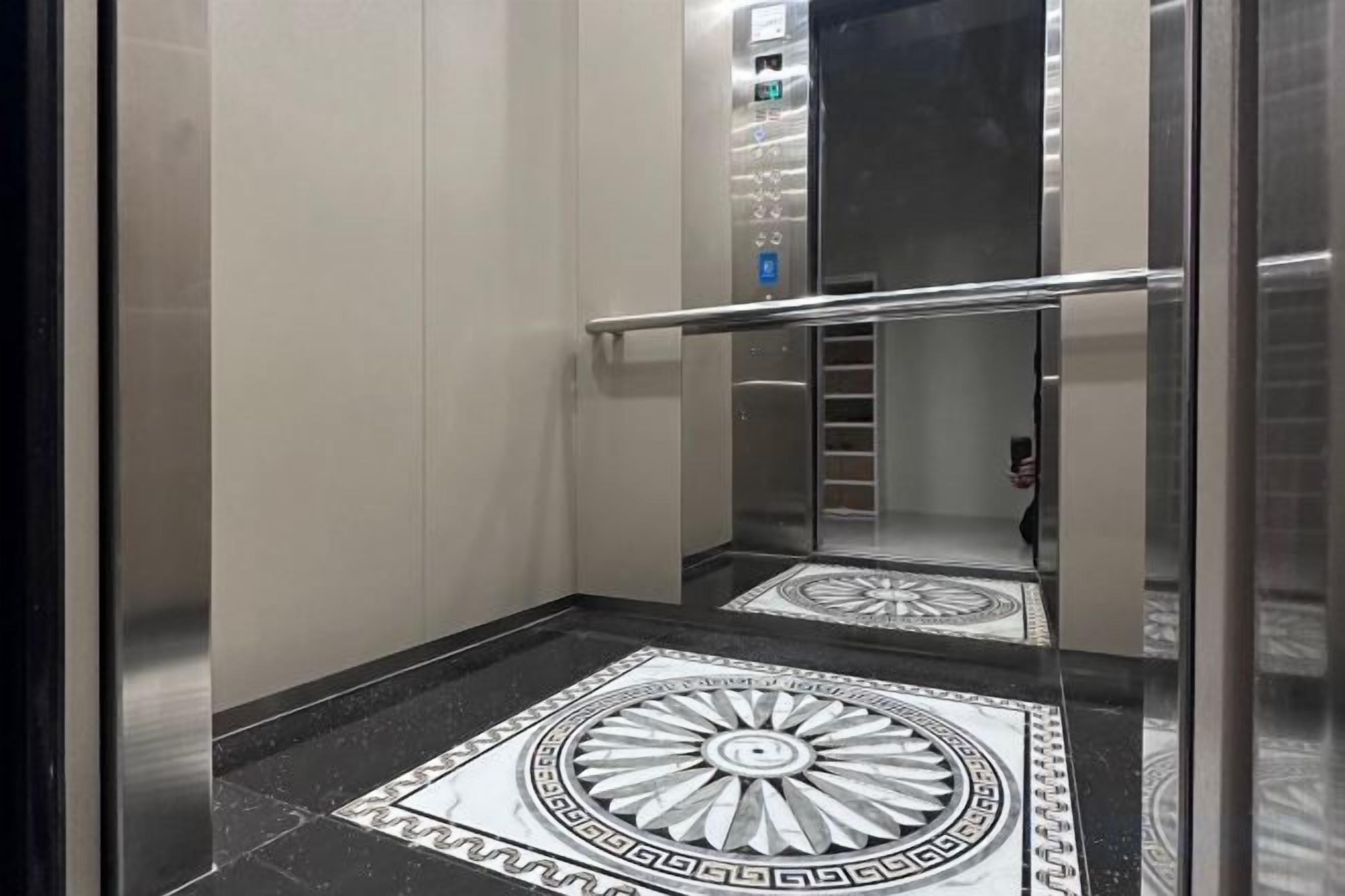 An elevator with a metallic handrail and a patterned floor.