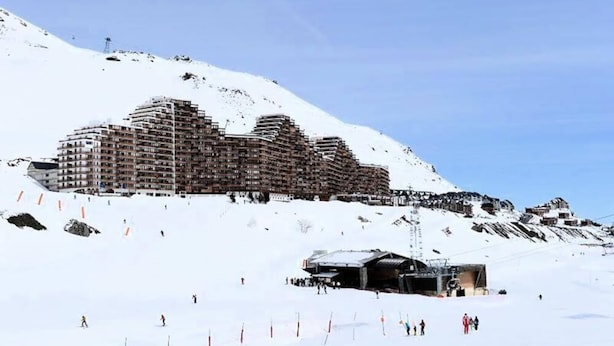 Een groot, meerlaags hotel met een modern architectuur, gelegen op een besneeuwde helling.