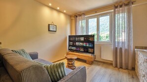 A cozy living room with a sofa, a wooden coffee table, and a flat-screen TV displaying a streaming service. - Scandinavian Suite with private Spa & Sauna - High-end escape (Nantua)