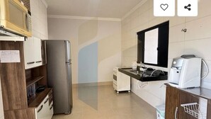 A compact kitchen with a refrigerator, microwave, sink, and coffee maker. - Cozy house in Caldas Novas with private heated pool. (Caldas Novas)
