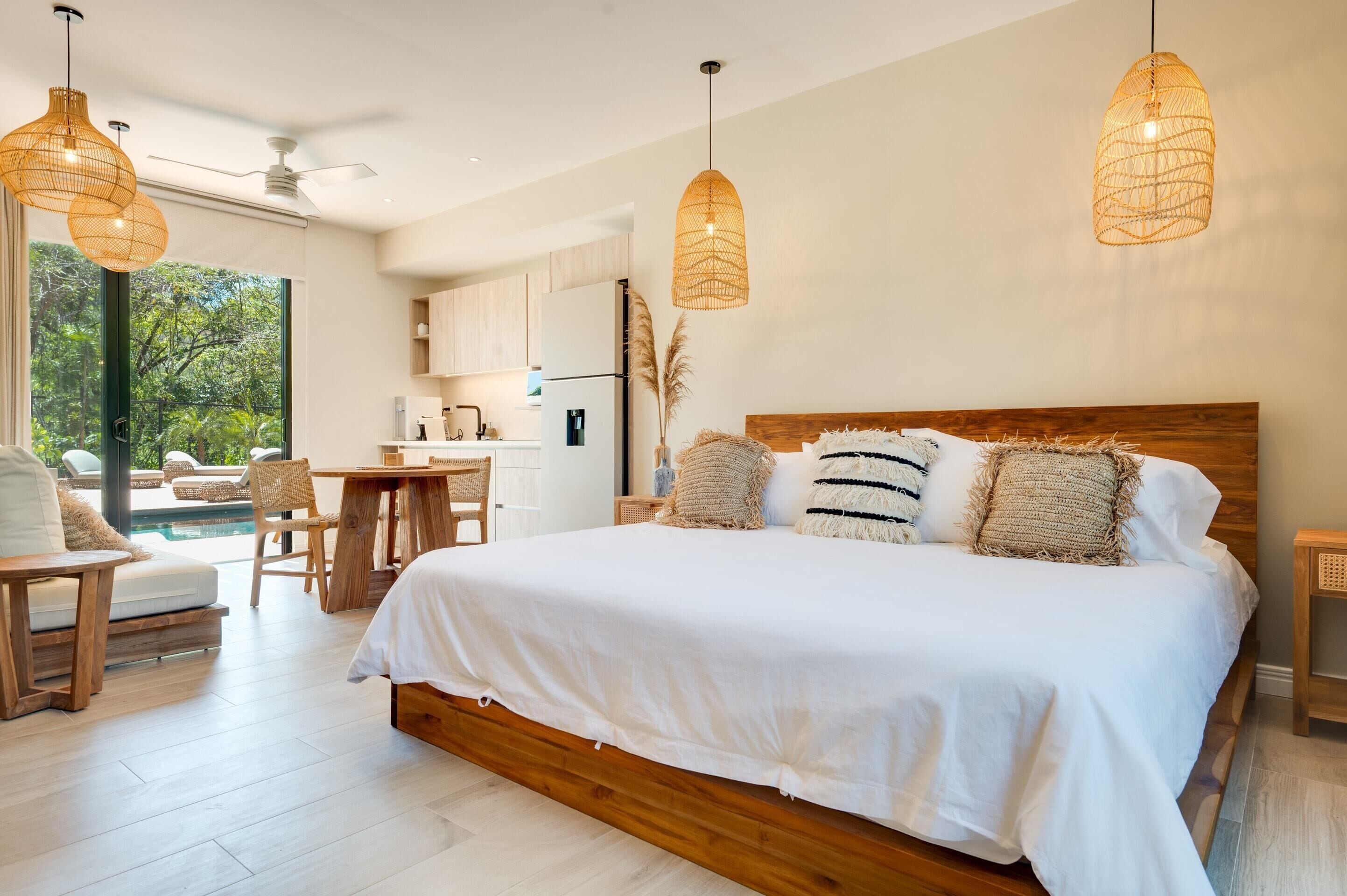 A bedroom with a large bed, wooden headboard, and two hanging wicker lamps.