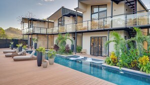 A modern two-story house with a swimming pool, outdoor seating, and lush landscaping. - The Bungalows-Flamingo (Playa Flamingo)