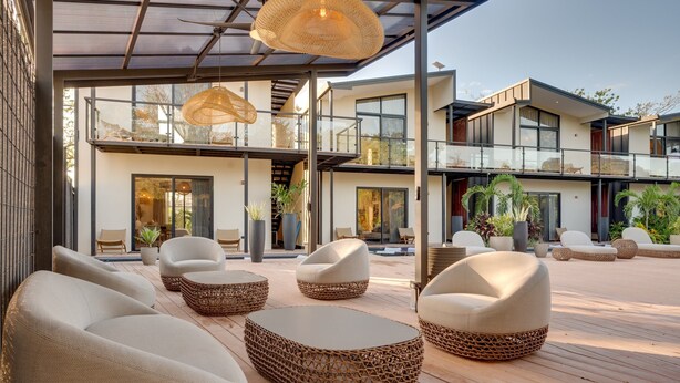 A modern outdoor seating area with wicker furniture and a glass balustrade. - The Bungalows-Flamingo (Playa Flamingo)