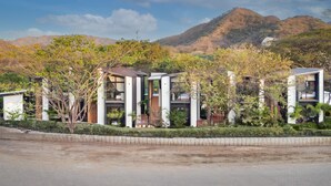 A modern residential area with contemporary houses, a well-maintained garden, and a mountainous backdrop. - The Bungalows-Flamingo (Playa Flamingo)
