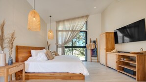 A modern bedroom with a wooden bed, large windows, a flat-screen TV, and a wooden cabinet. - The Bungalows-Flamingo (Playa Flamingo)
