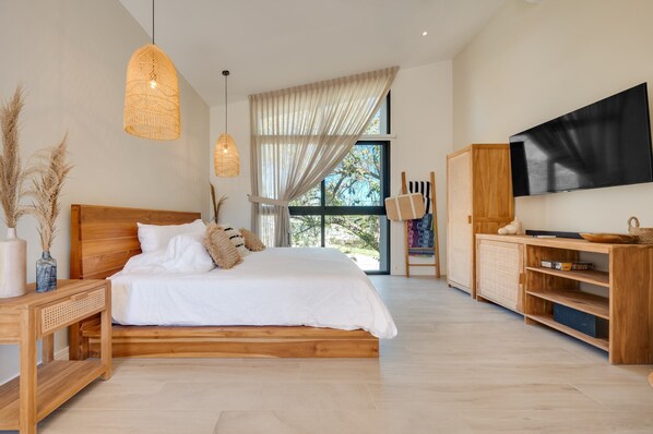 A modern bedroom with a wooden bed, large windows, a flat-screen TV, and a wooden cabinet. - The Bungalows-Flamingo (Playa Flamingo)