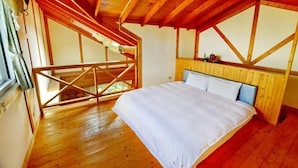 Un dormitorio con techo de madera, una cama con ropa de cama blanca y una ventana.