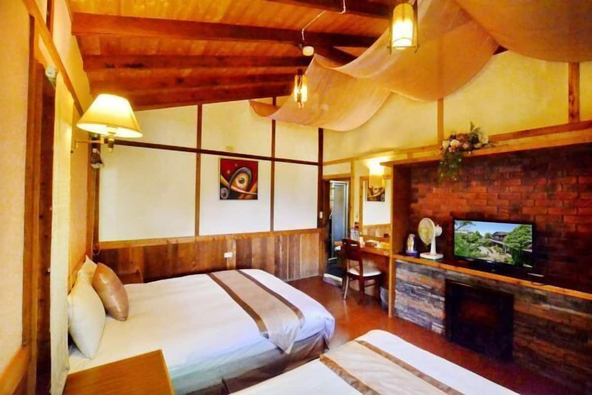A cozy room with two beds, a desk, a television, and a fireplace.