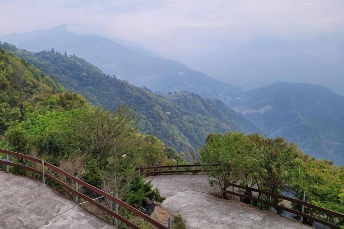A mountainous landscape with a stone pathway and wooden railing.