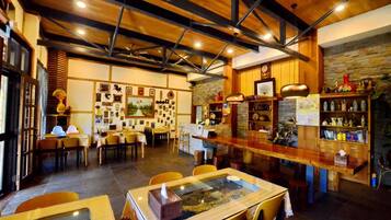 A restaurant interior with wooden beams, a bar area, and various framed pictures on the walls.