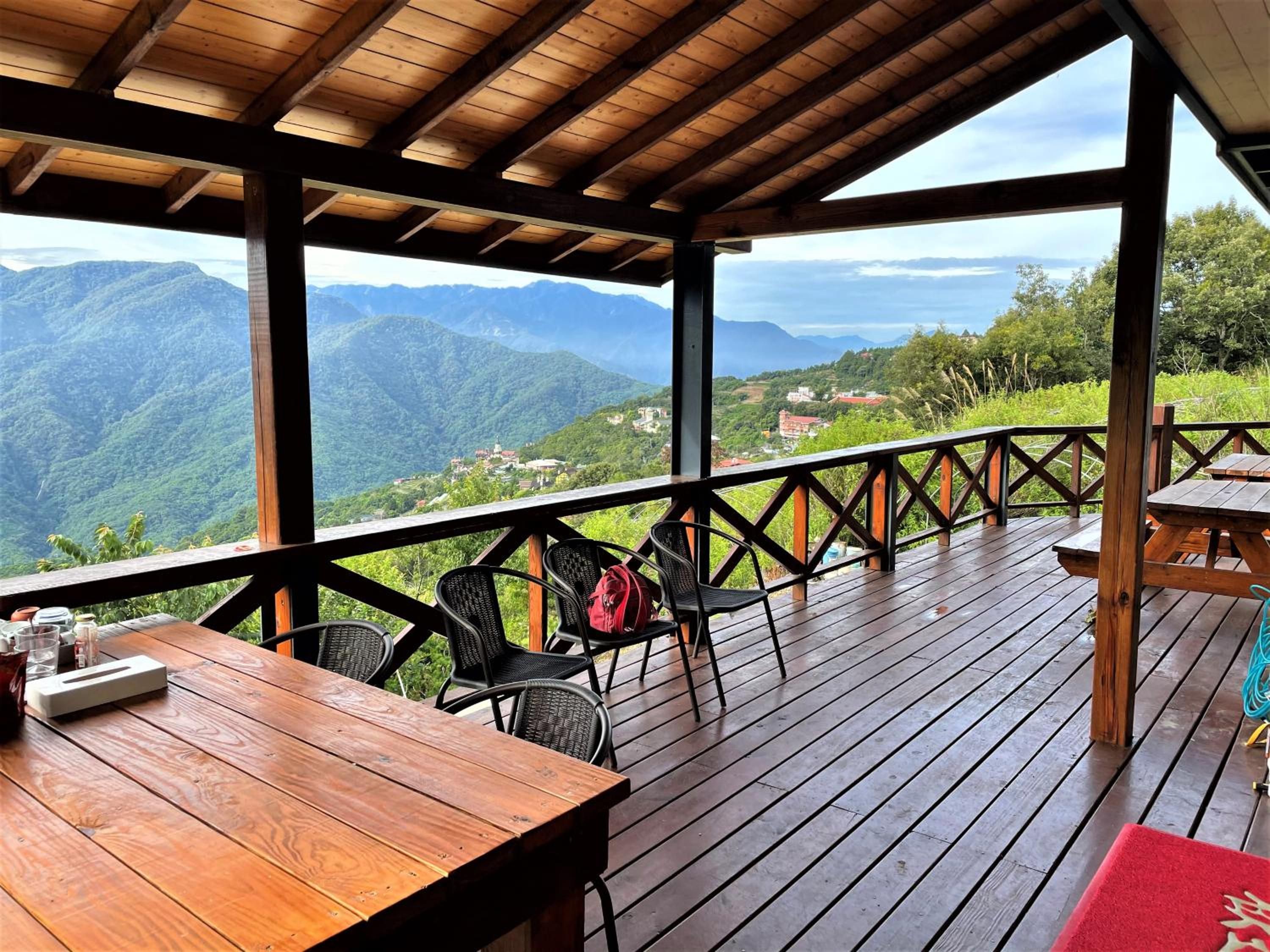 A wooden deck with a table and chairs, overlooking a mountainous landscape.