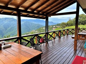 A wooden deck with a table and chairs, overlooking a mountainous landscape. - Shiyai Taoyuan B & B (Nantou)