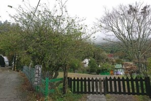 A pathway leading to a fenced area with a sign, a wooden fence, and a building in the background. - Shiwai Taoyuan B&B (Nantou)