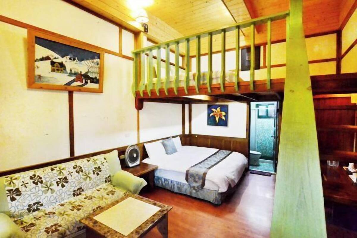 A room with a bunk bed, a sofa, a fan, and a painting on the wall.
