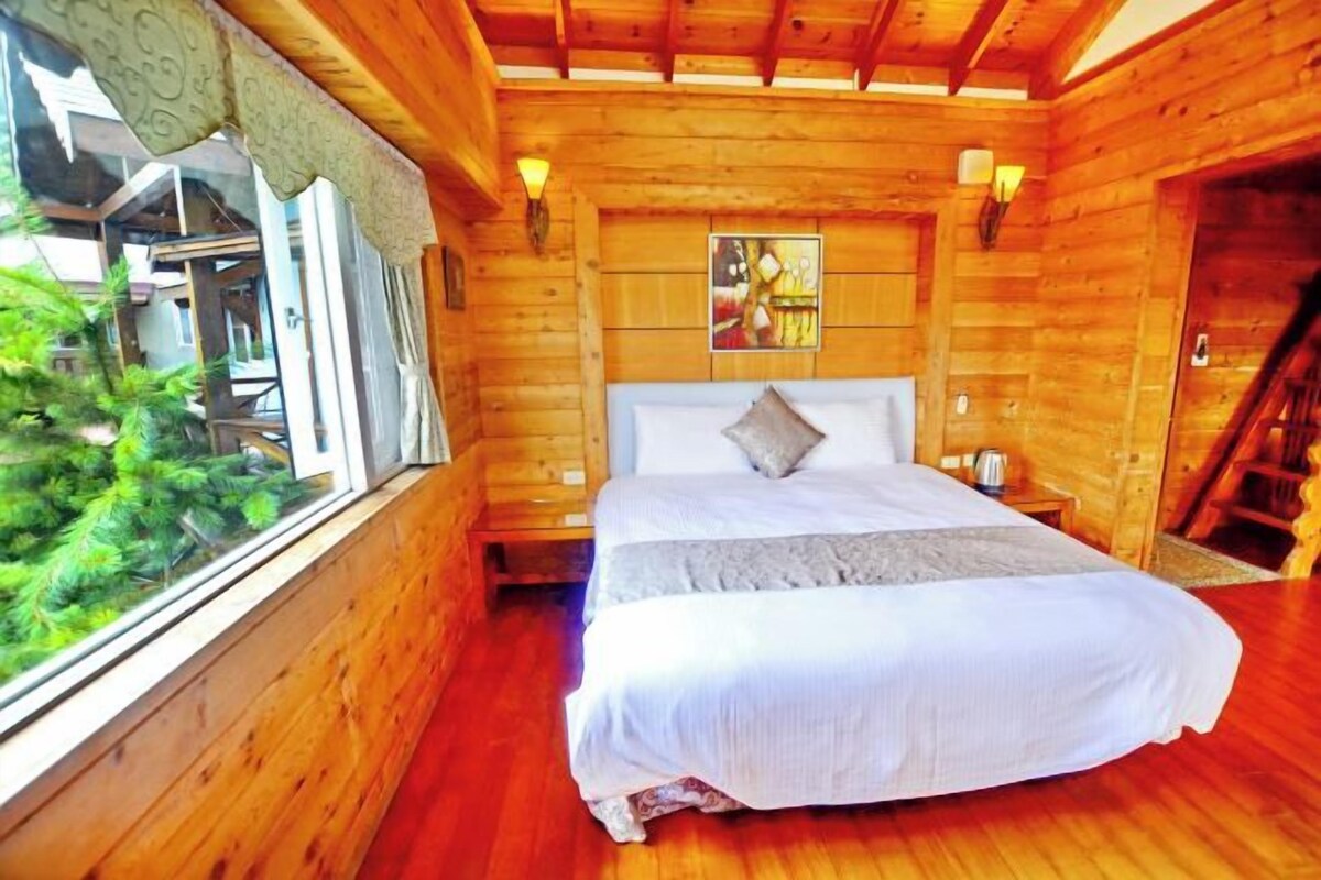 Un dormitori de cabana de fusta amb un llit, una finestra i un quadre a la paret.