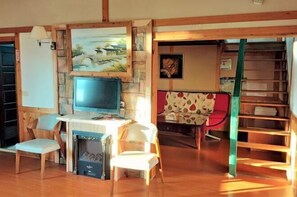 A cozy room with a fireplace, a television, and a bookshelf. - Shiwai Taoyuan B&B (Nantou)