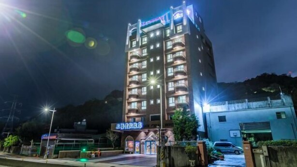 A multi-story hotel with illuminated signage and a well-lit entrance. - San Chiao Hotel (Taoyuan)