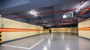 An empty parking garage with marked parking spaces, red safety railings, and visible structural beams. - San Chiao Hotel (Taoyuan)